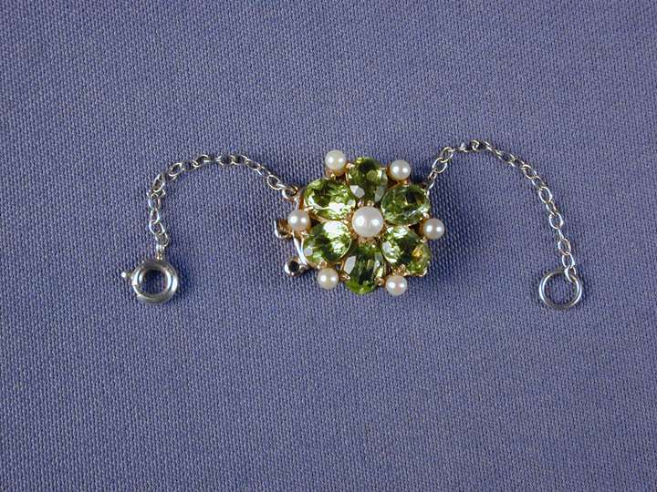 Peridot and pearl circular cluster snap with a central pearl and six oval peridots